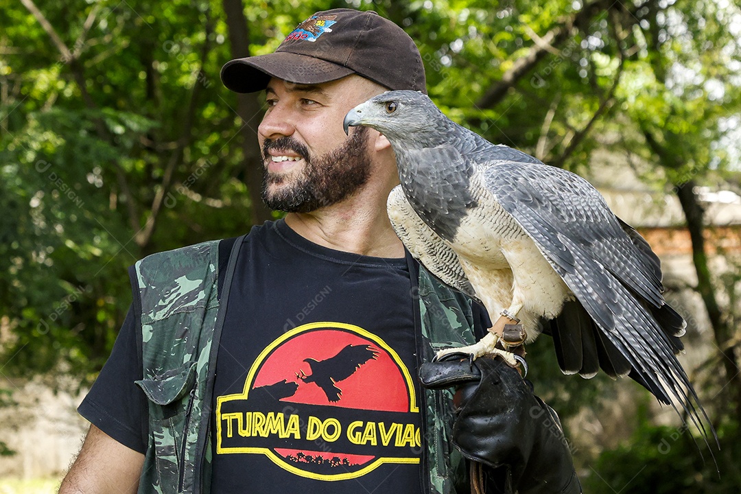 Homem jovem sobre campo verde com seu animal de estimação águia