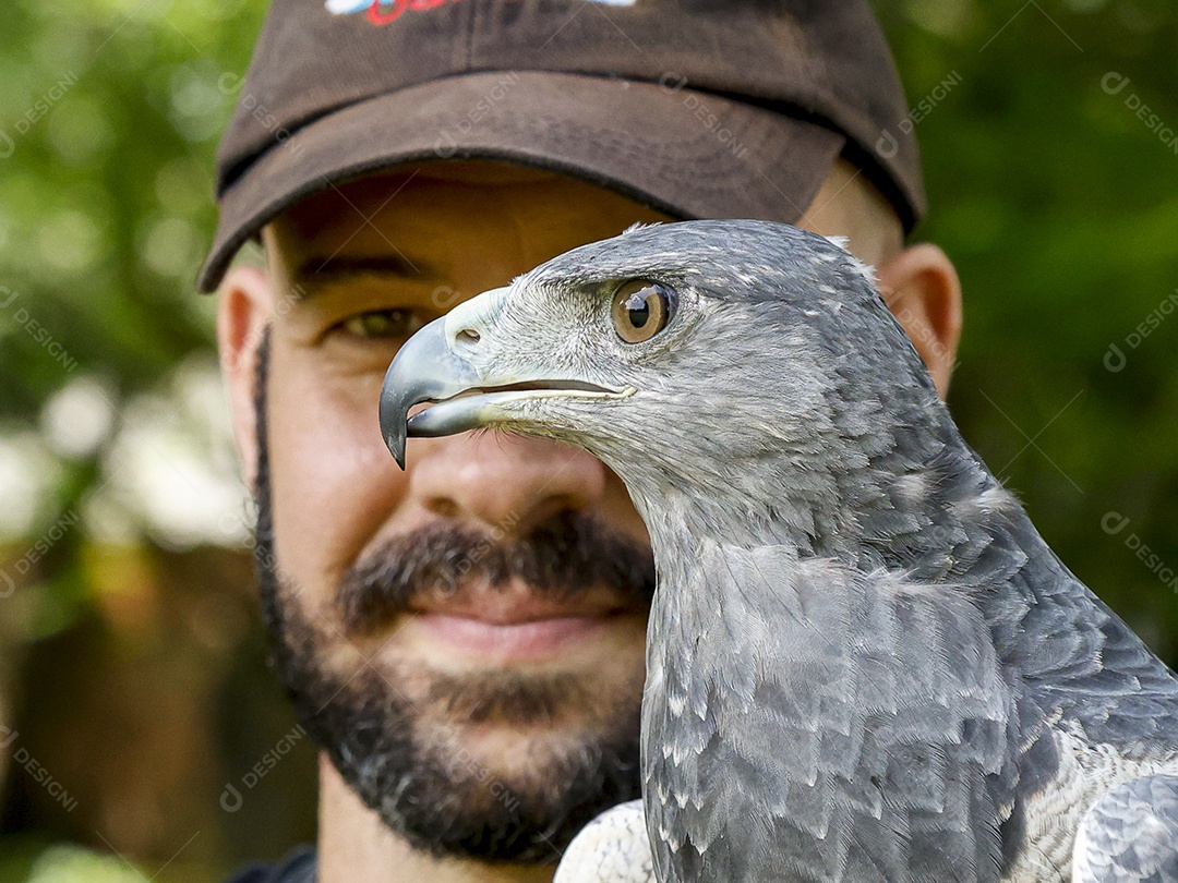 Homem jovem sobre campo verde com seu animal de estimação águia