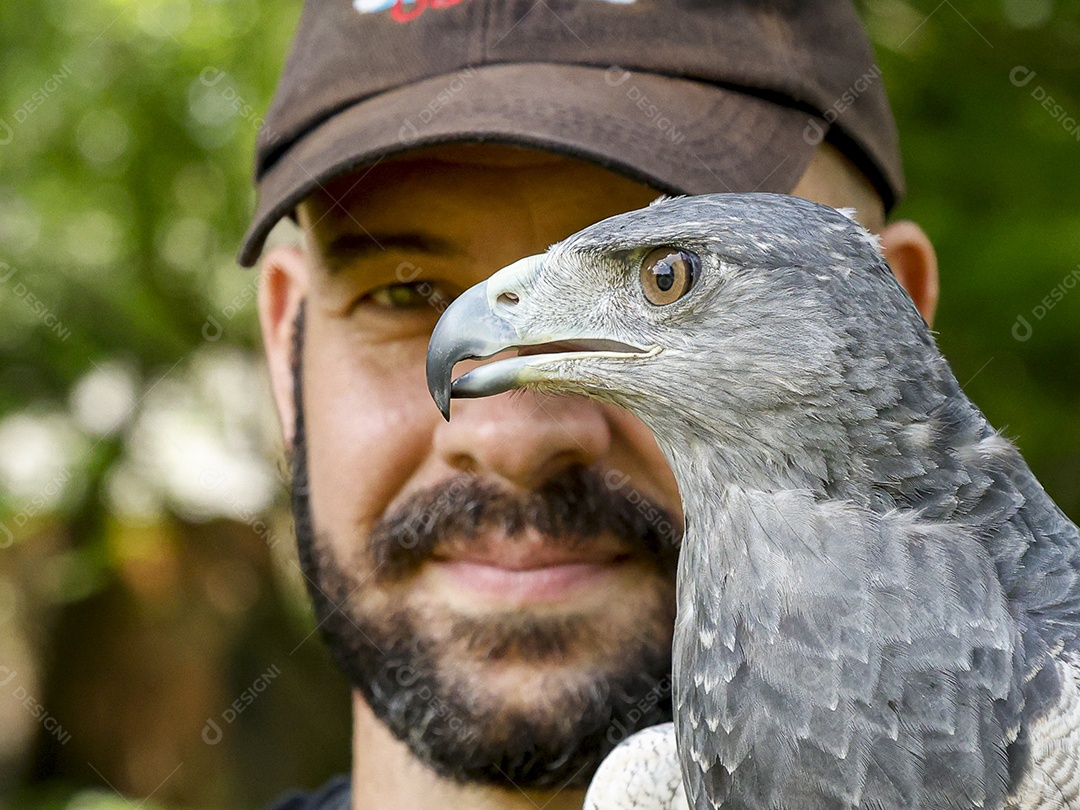 Homem jovem sobre campo verde com seu animal de estimação águia