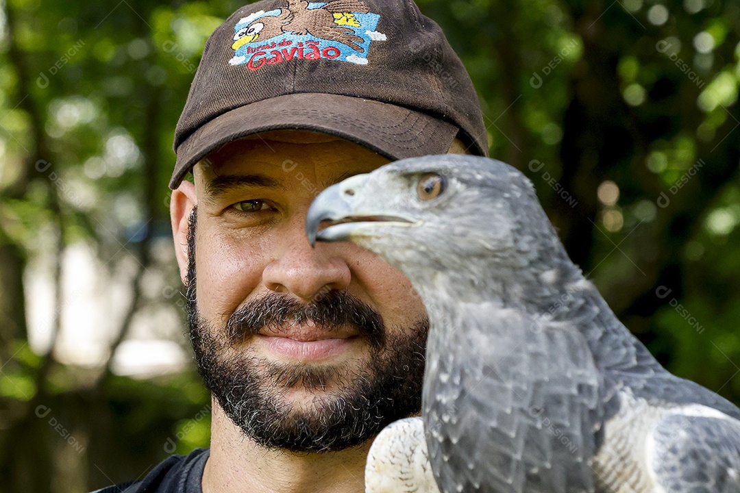 Homem jovem sobre campo verde com seu animal de estimação águia