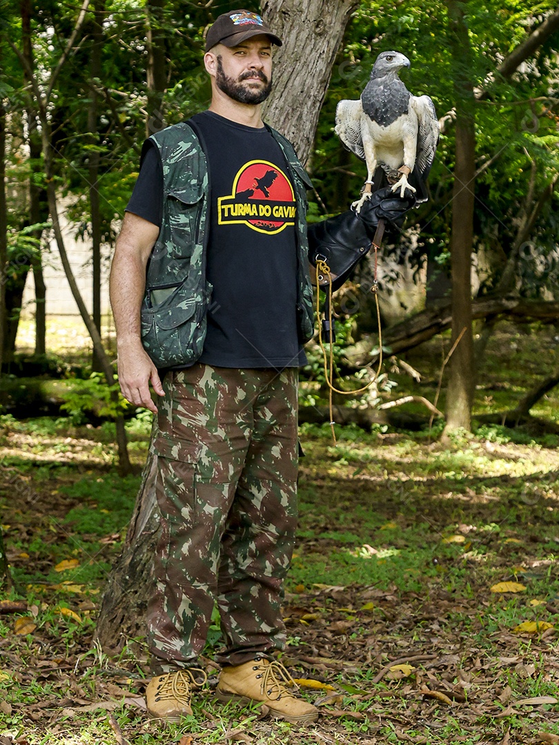 Homem jovem sobre campo verde com seu animal de estimação águia