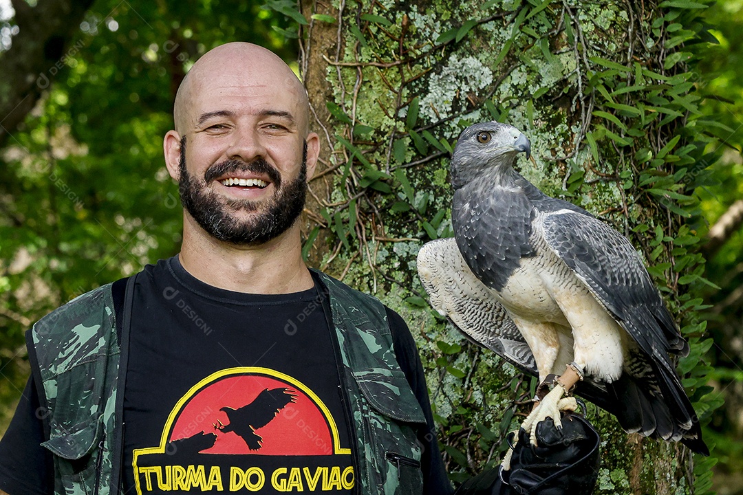 Homem jovem sobre campo verde com seu animal de estimação águia