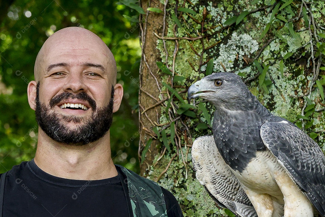 Homem jovem sobre campo verde com seu animal de estimação águia