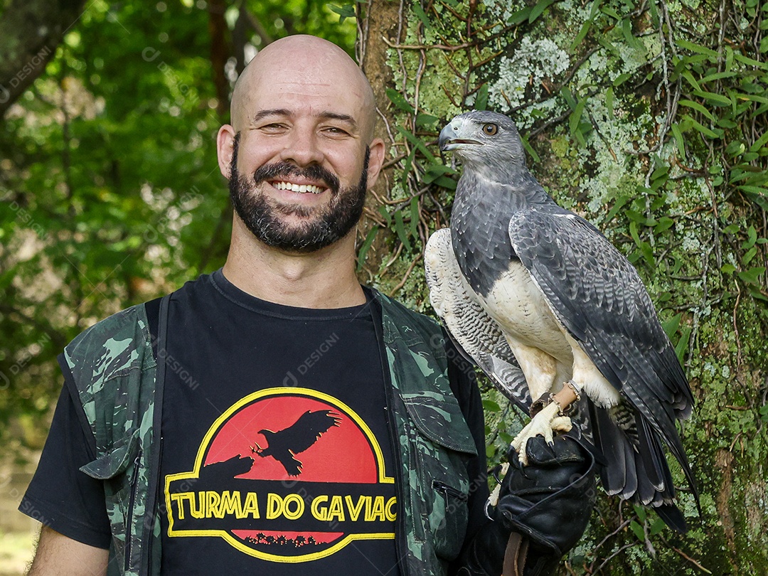 Homem jovem sobre campo verde com seu animal de estimação águia