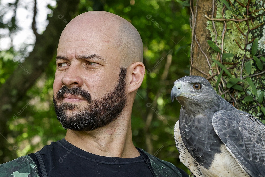Homem jovem sobre campo verde com seu animal de estimação águia