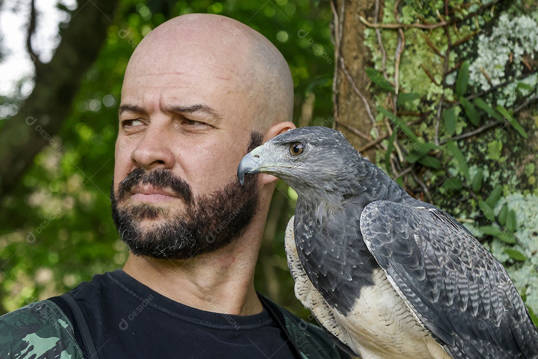 Homem jovem sobre campo verde com seu animal de estimação águia