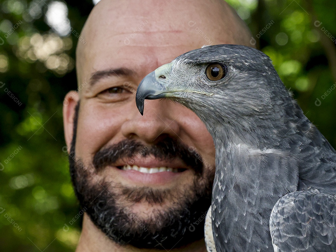 Homem jovem sobre campo verde com seu animal de estimação águia