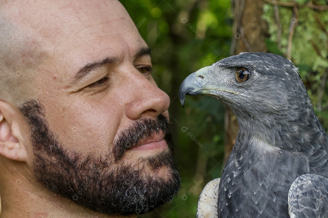 Homem jovem sobre campo verde com seu animal de estimação águia