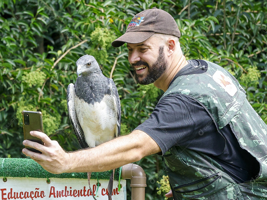 Homem jovem sobre campo verde com seu animal de estimação águia
