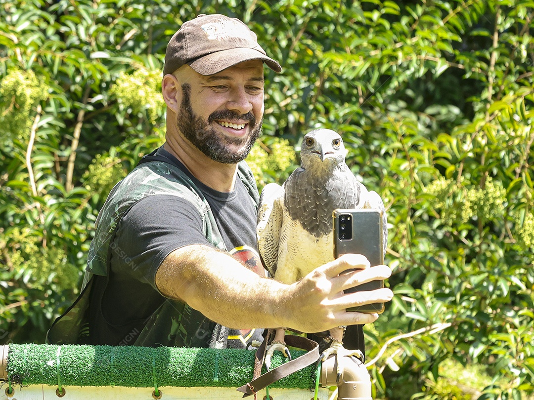 Homem jovem sobre campo verde com seu animal de estimação águia