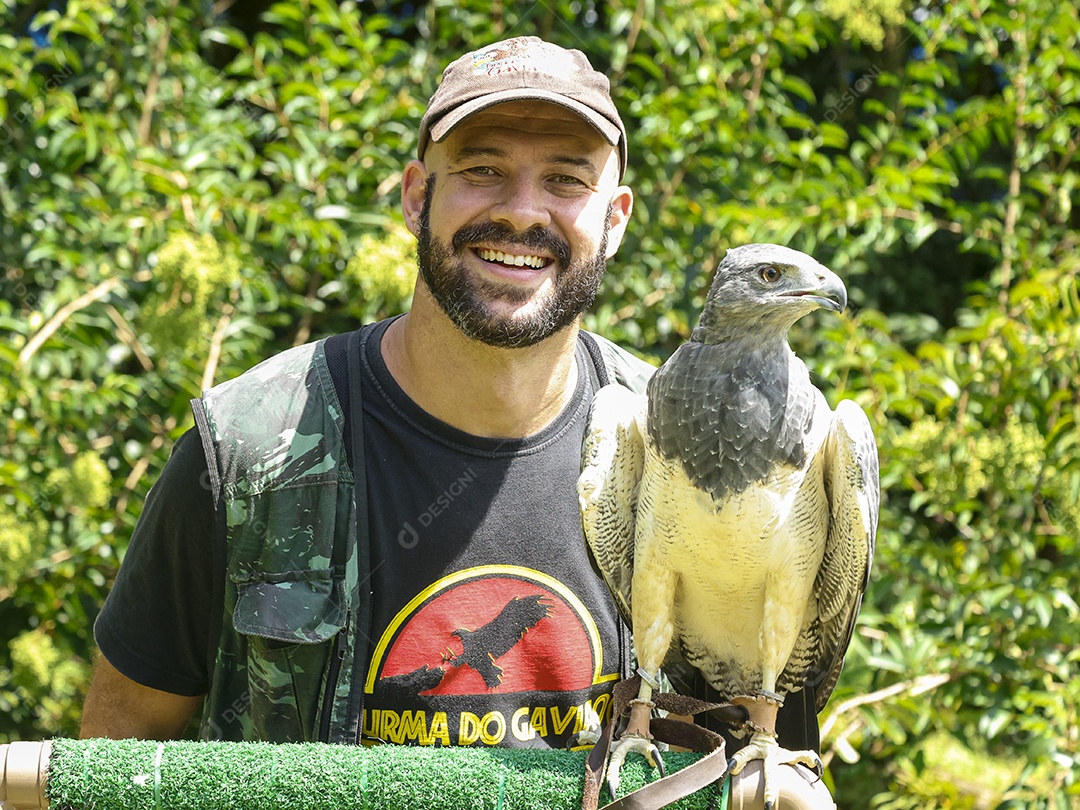 Homem jovem sobre campo verde com seu animal de estimação águia