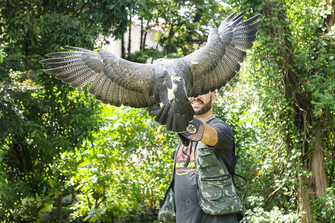 Homem jovem sobre campo verde com seu animal de estimação águia