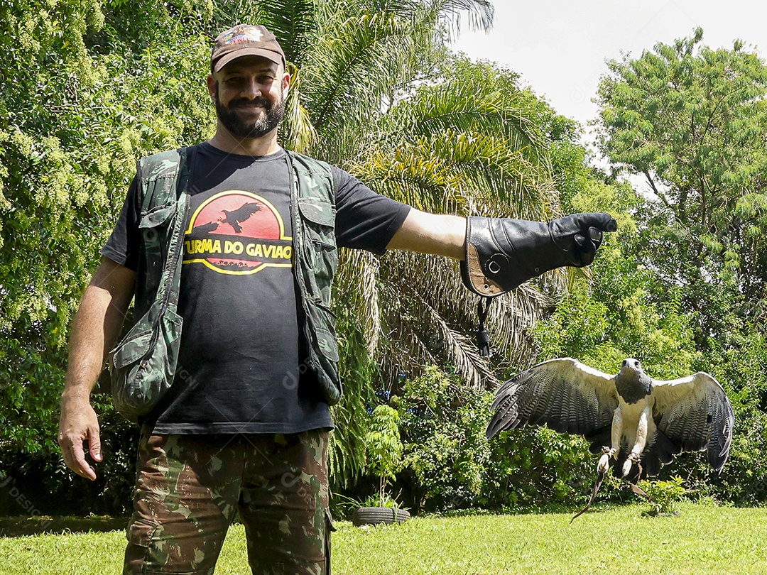 Homem jovem sobre campo verde com seu animal de estimação águia