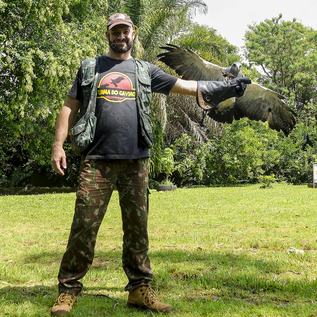 Homem jovem sobre campo verde com seu animal de estimação águia