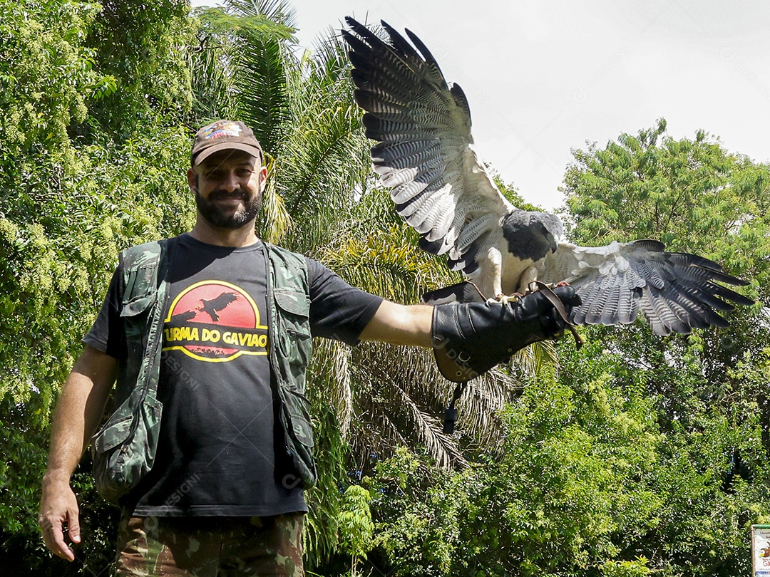 Homem jovem sobre campo verde com seu animal de estimação águia