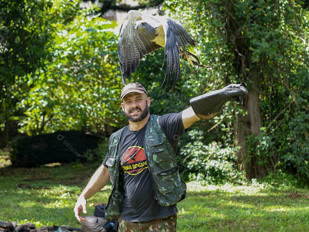 Homem jovem sobre campo verde com seu animal de estimação águia