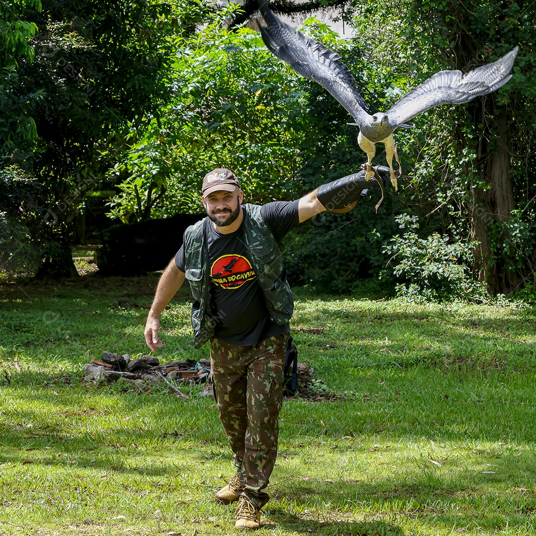 Homem jovem sobre campo verde com seu animal de estimação águia