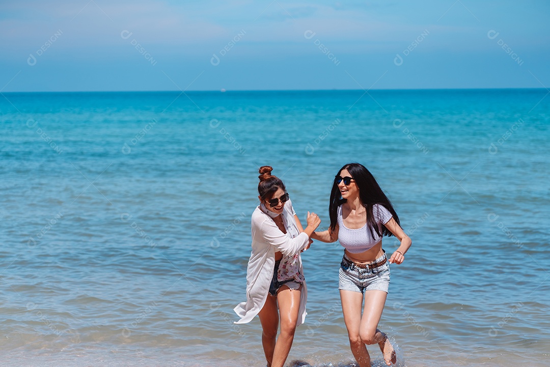 Felizes duas amigas curtindo juntas na praia.