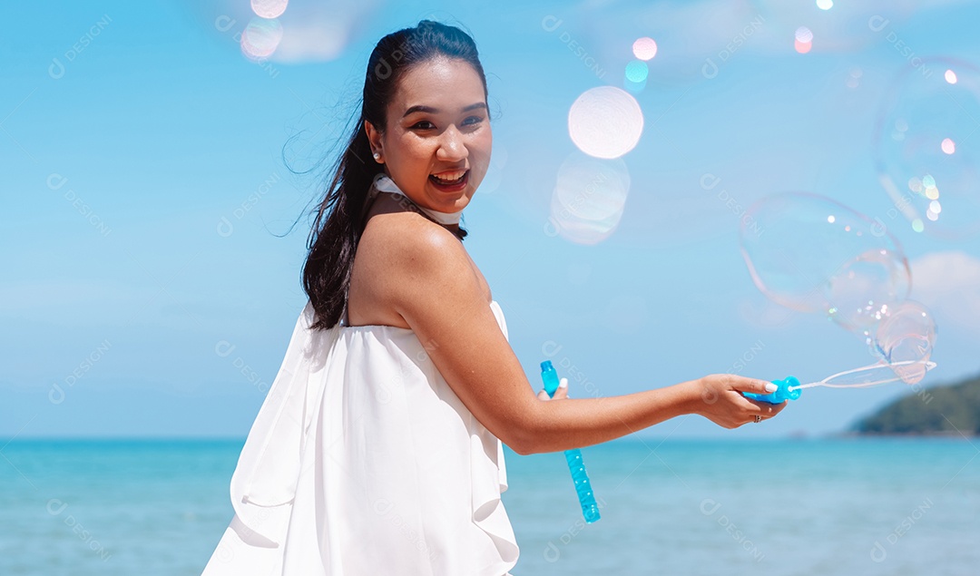 Feliz e bela jovem asiática soprando bolhas de sabão