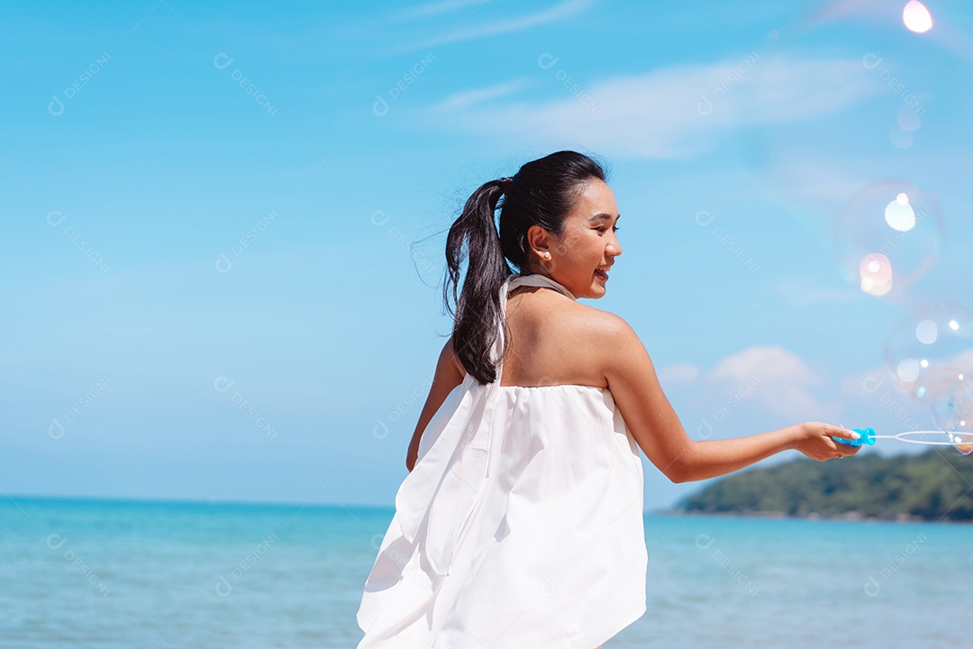 Feliz e bela jovem asiática soprando bolhas de sabão