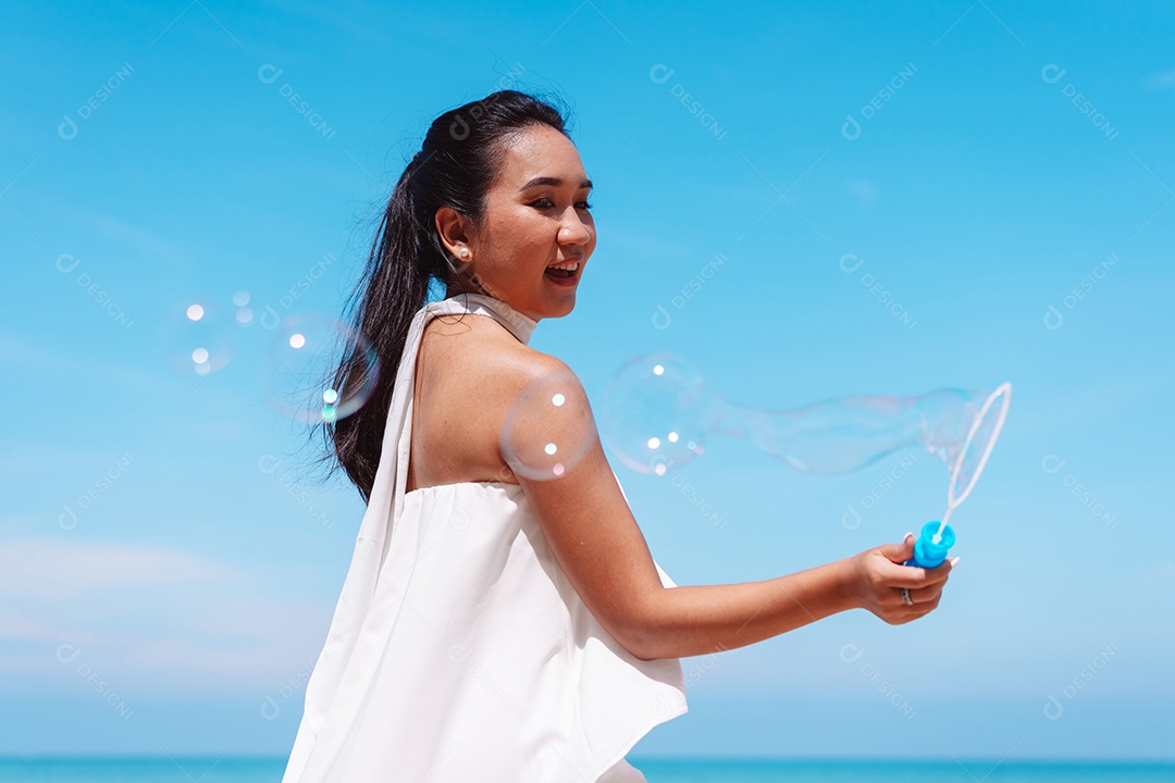 Feliz e bela jovem asiática soprando bolhas de sabão