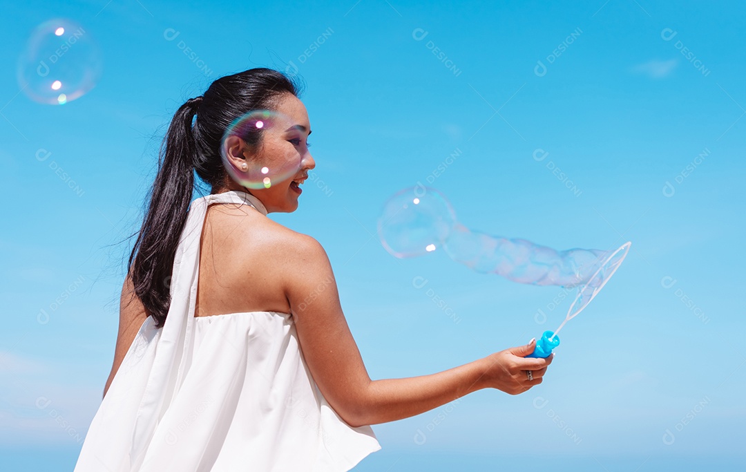 Feliz e bela jovem asiática soprando bolhas de sabão