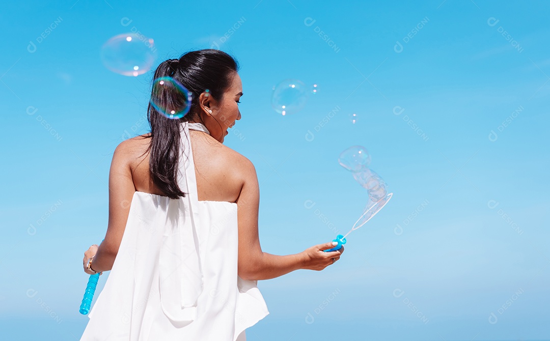 Feliz e bela jovem asiática soprando bolhas de sabão