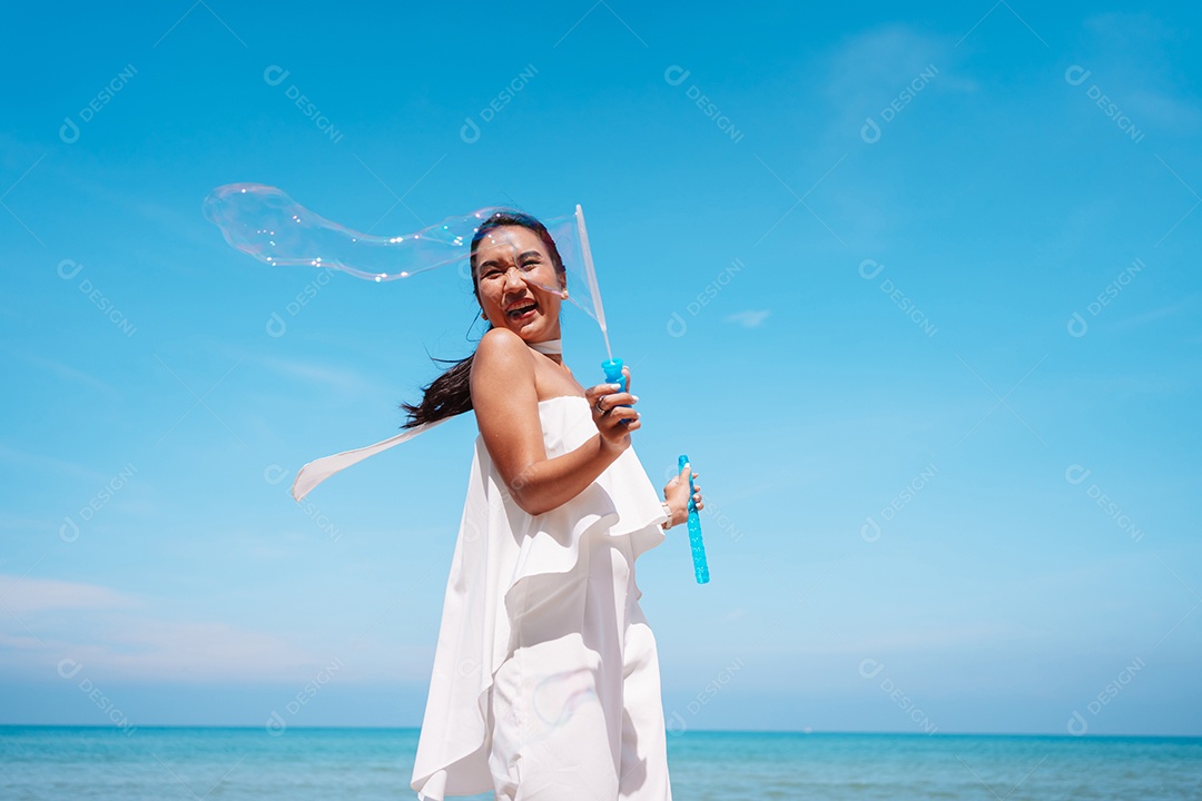 Feliz e bela jovem asiática soprando bolhas de sabão