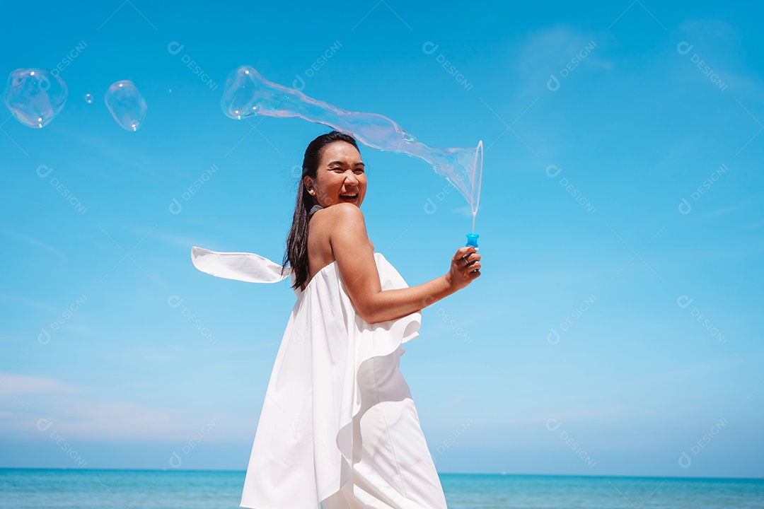 Feliz e bela jovem asiática soprando bolhas de sabão