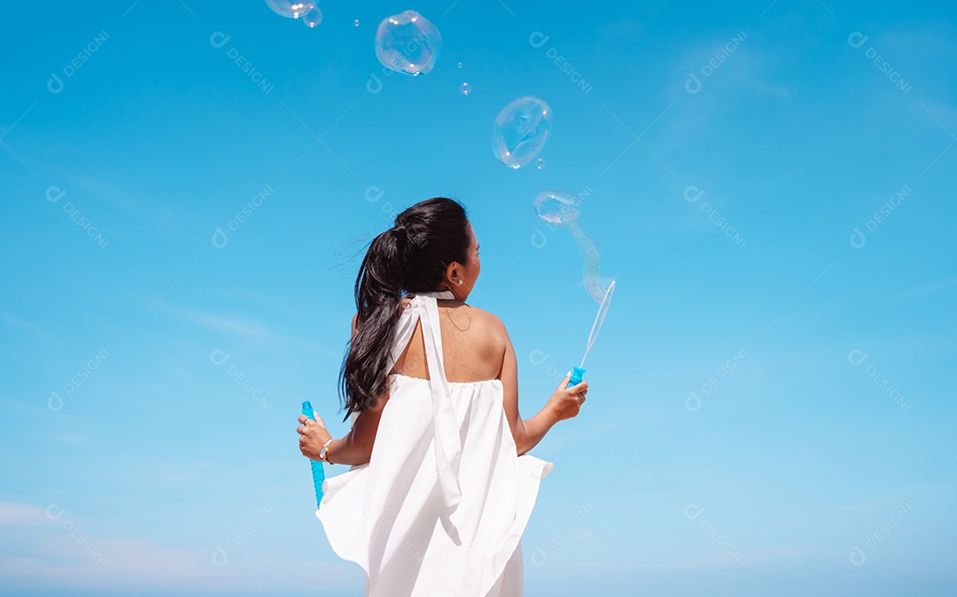 Feliz e bela jovem asiática soprando bolhas de sabão