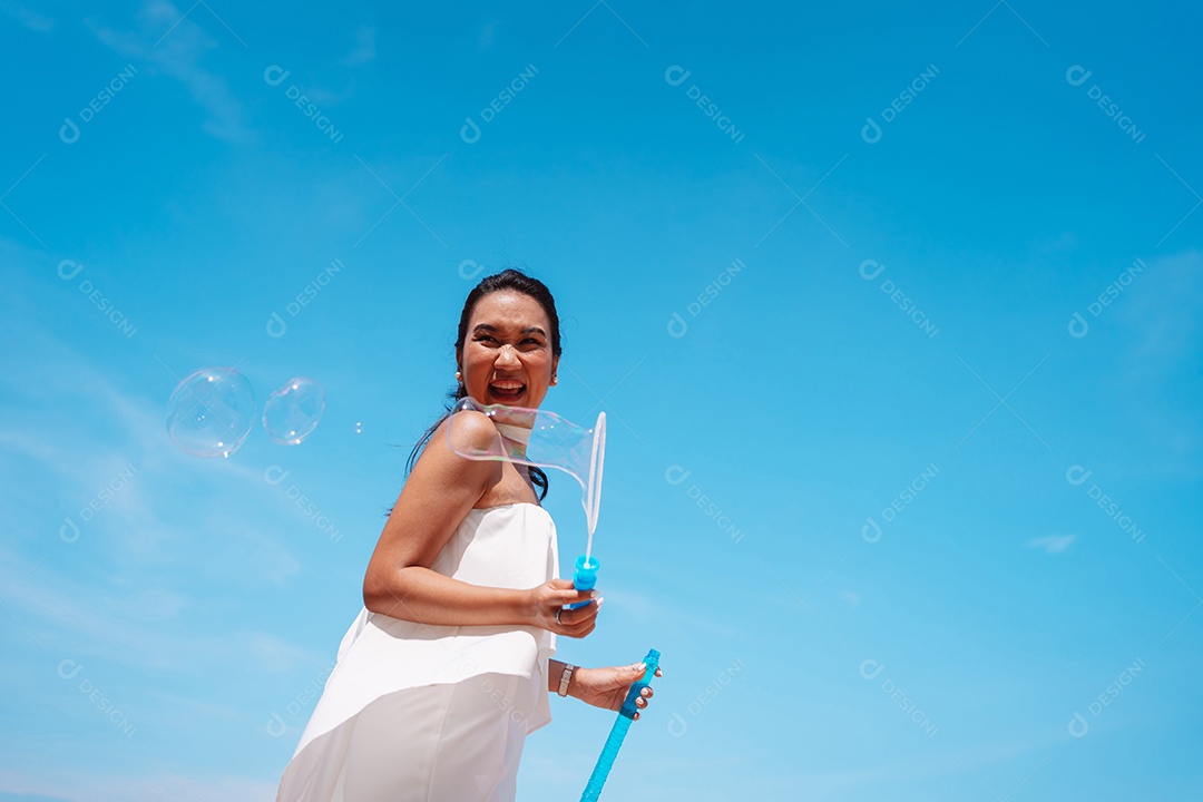 Feliz e bela jovem asiática soprando bolhas de sabão