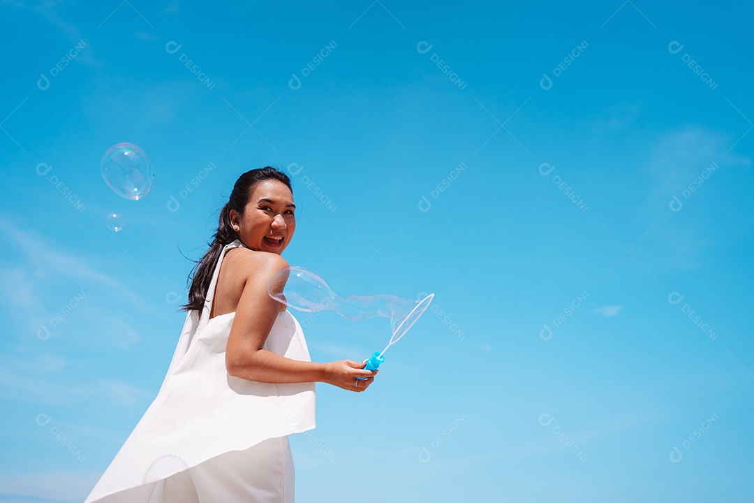 Feliz e bela jovem asiática soprando bolhas de sabão