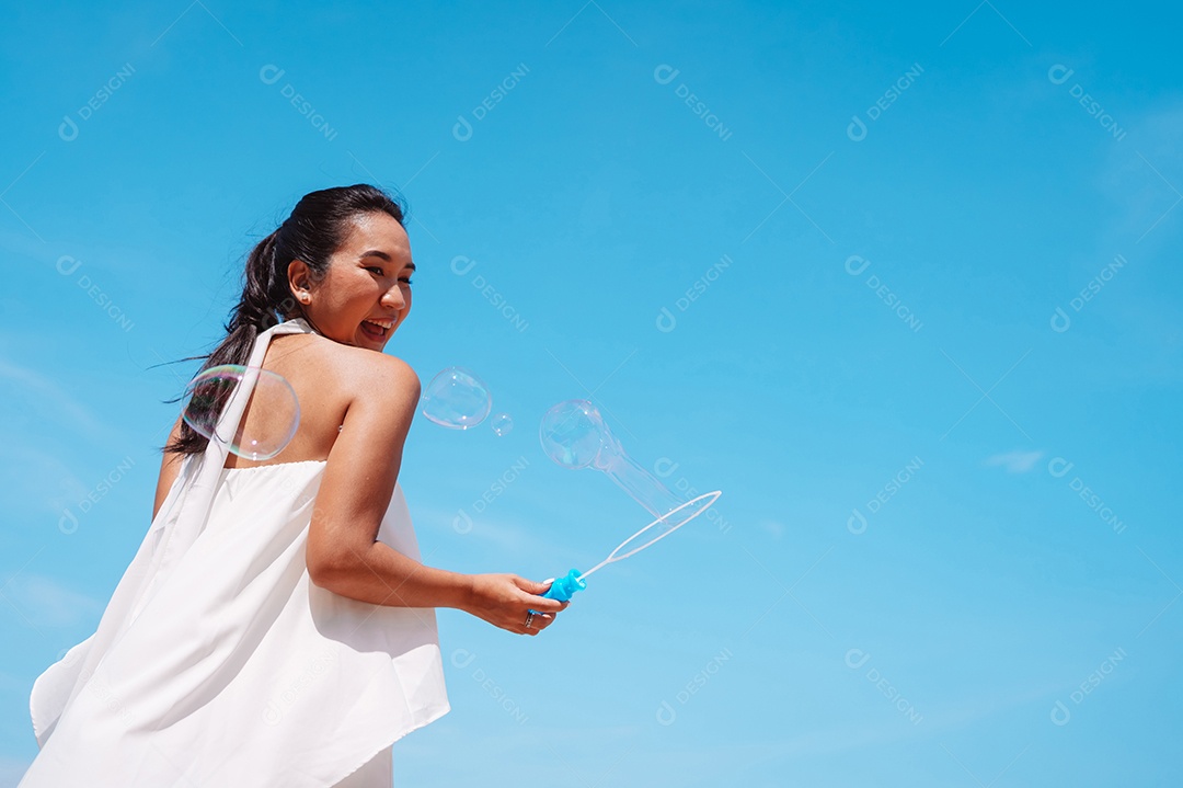 Feliz e bela jovem asiática soprando bolhas de sabão