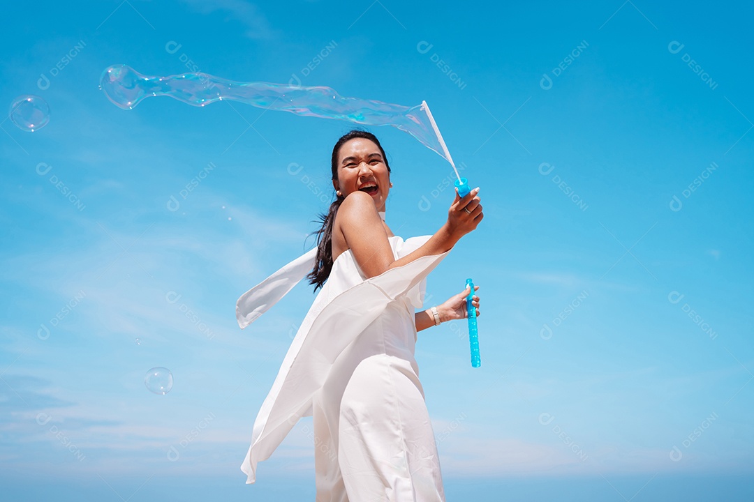 Feliz e bela jovem asiática soprando bolhas de sabão