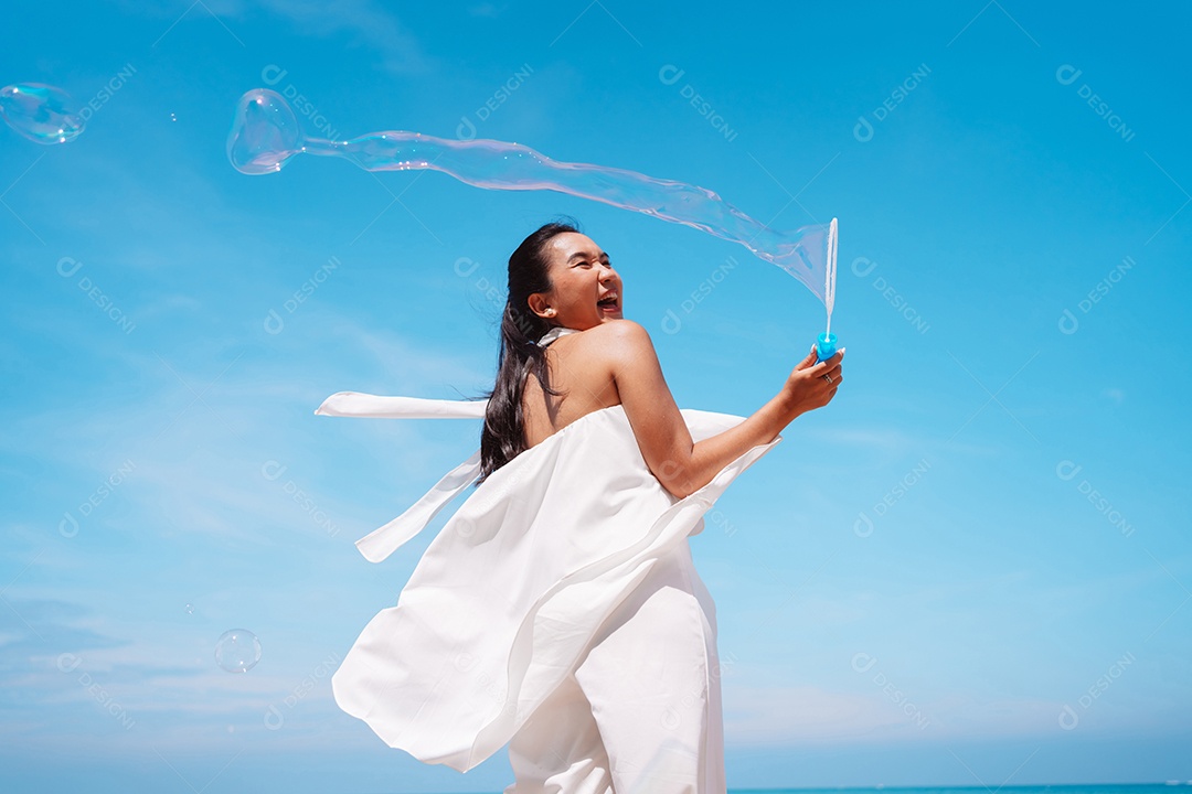 Feliz e bela jovem asiática soprando bolhas de sabão