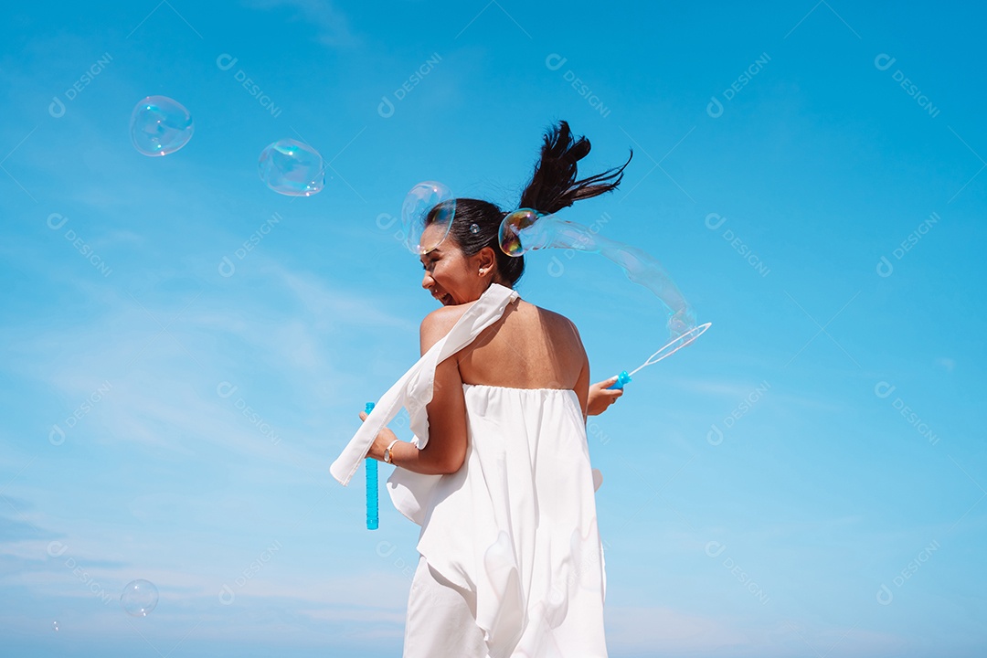 Feliz e bela jovem asiática soprando bolhas de sabão