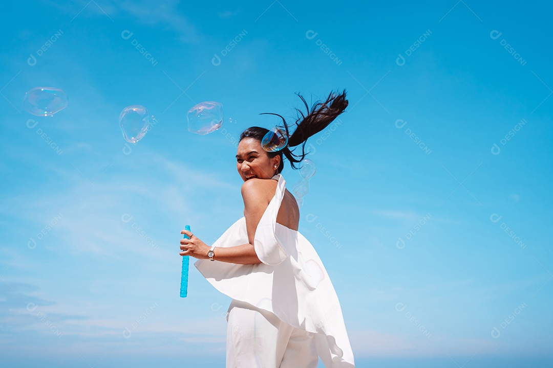 Feliz e bela jovem asiática soprando bolhas de sabão