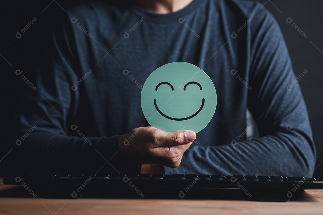 Mão segurando o corte de papel de rosto sorridente feliz, boa classificação de feedback e avaliação positiva do cliente