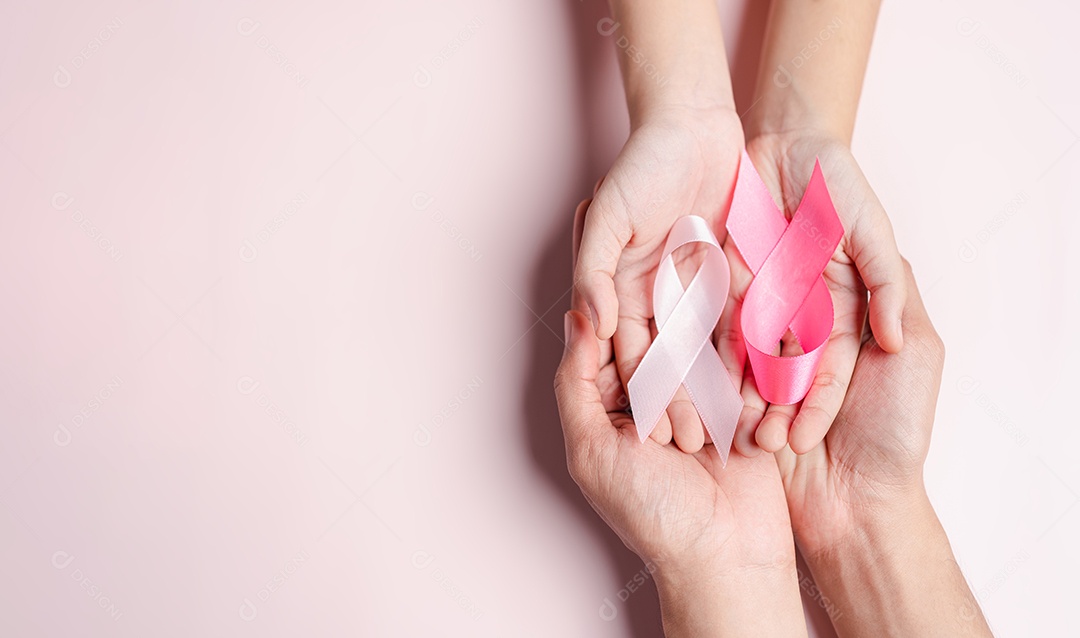 Mãos de pessoas segurando fitas rosa em fundo rosa, conscientização sobre o câncer de mama