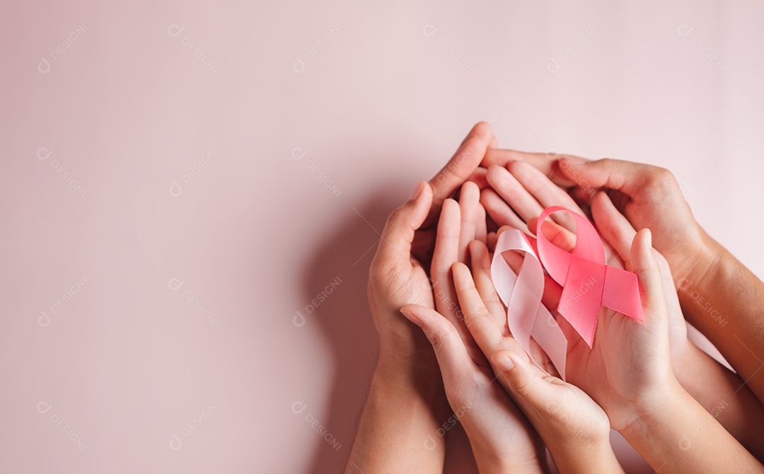 Mãos de pessoas segurando fitas rosa em fundo rosa, conscientização sobre o câncer de mama