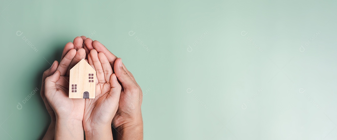 mãos segurando casa de madeira, casa de família