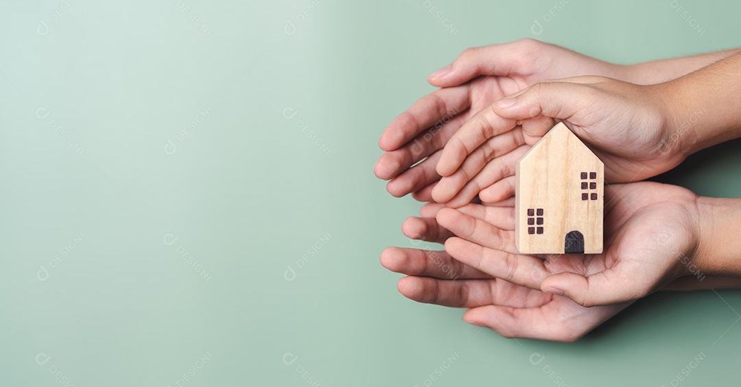 Mãos segurando casa de madeira