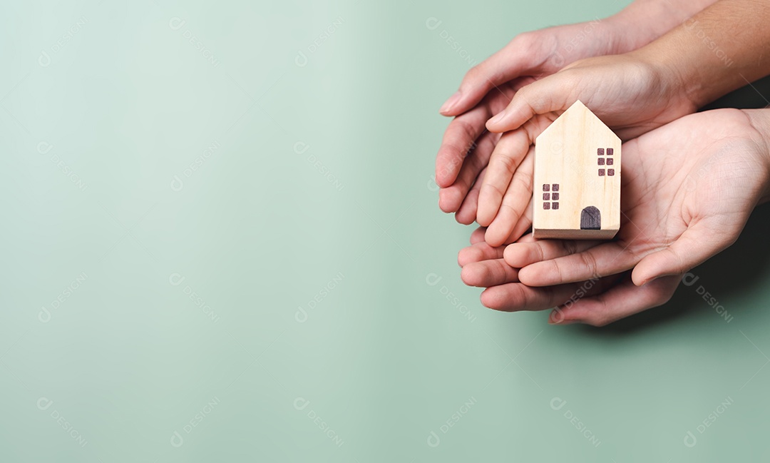 Mãos segurando casa de madeira