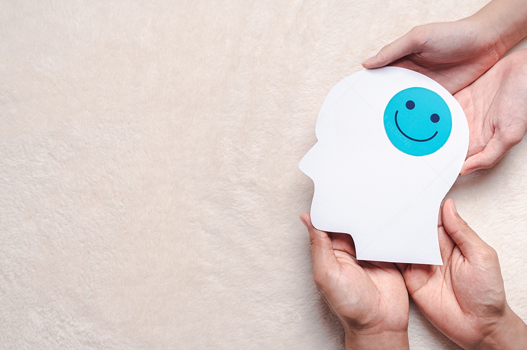Mãos segurando um rosto sorridente em corte de papel cerebral, emoção sorridente feliz