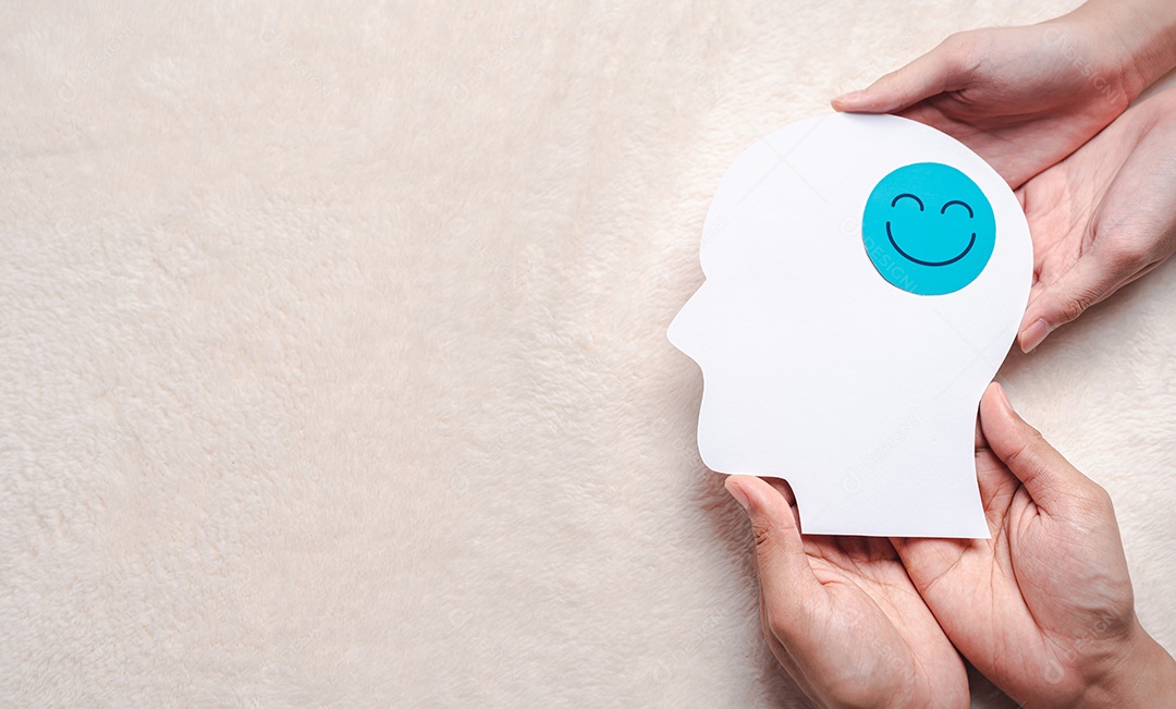 Mãos segurando um rosto sorridente em corte de papel cerebral, emoção sorridente feliz