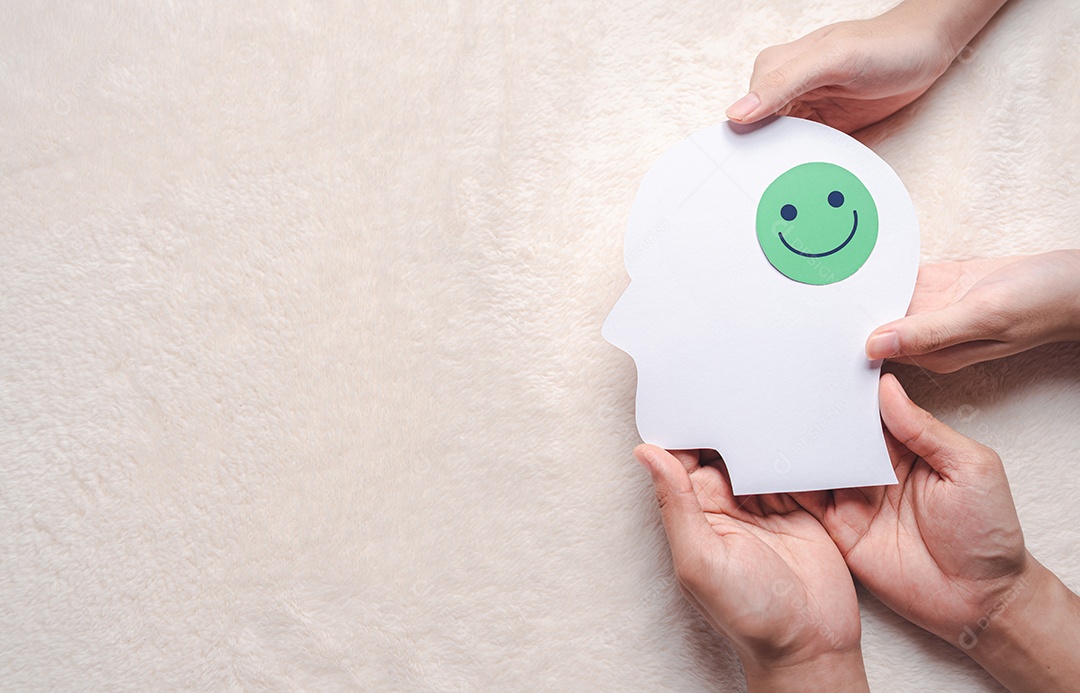 Mãos segurando um rosto sorridente em corte de papel cerebral, emoção sorridente feliz