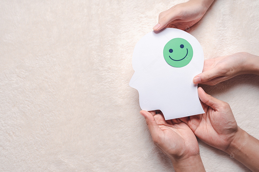 Mãos segurando um rosto sorridente em corte de papel cerebral, emoção sorridente feliz