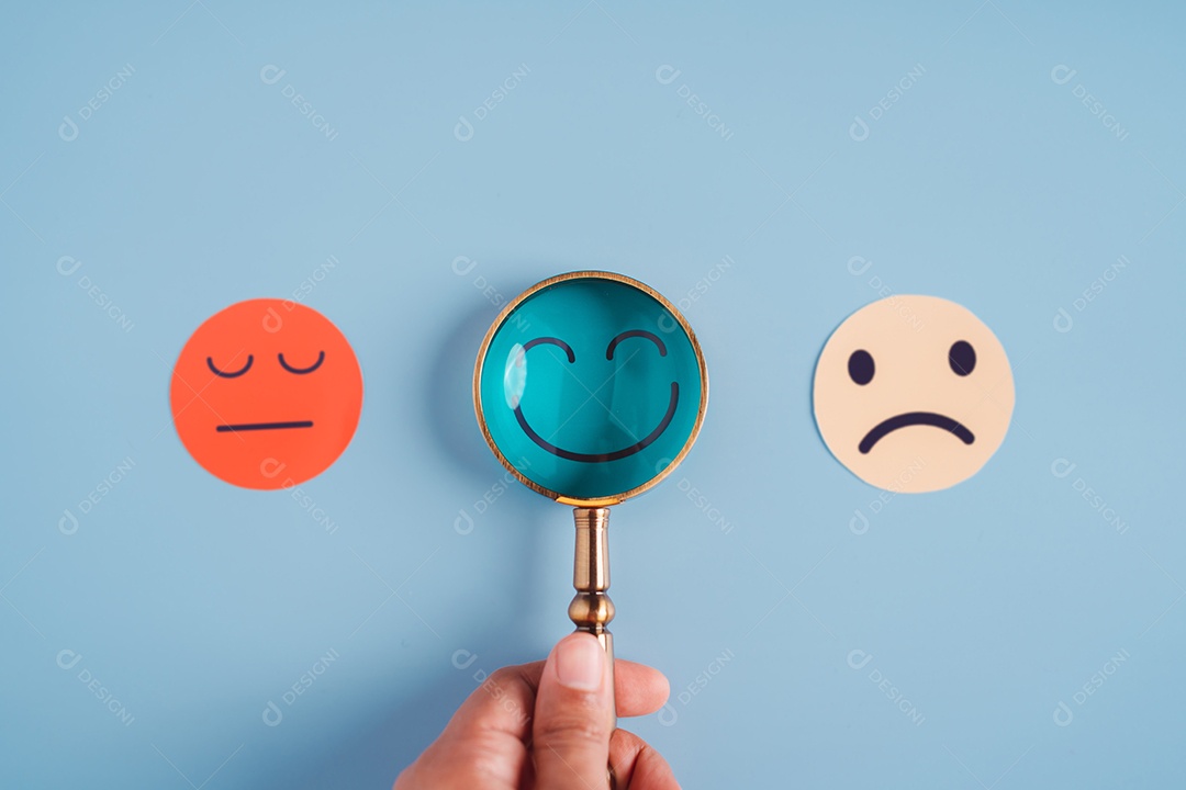 Mão segurando lupa foco selecionado corte de papel de rosto sorridente feliz que está entre várias emoções