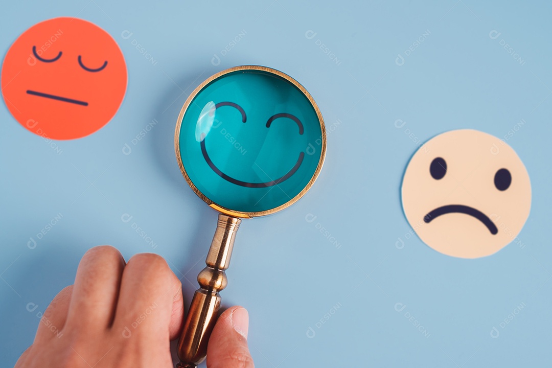 Mão segurando lupa foco selecionado corte de papel de rosto sorridente feliz que está entre várias emoções