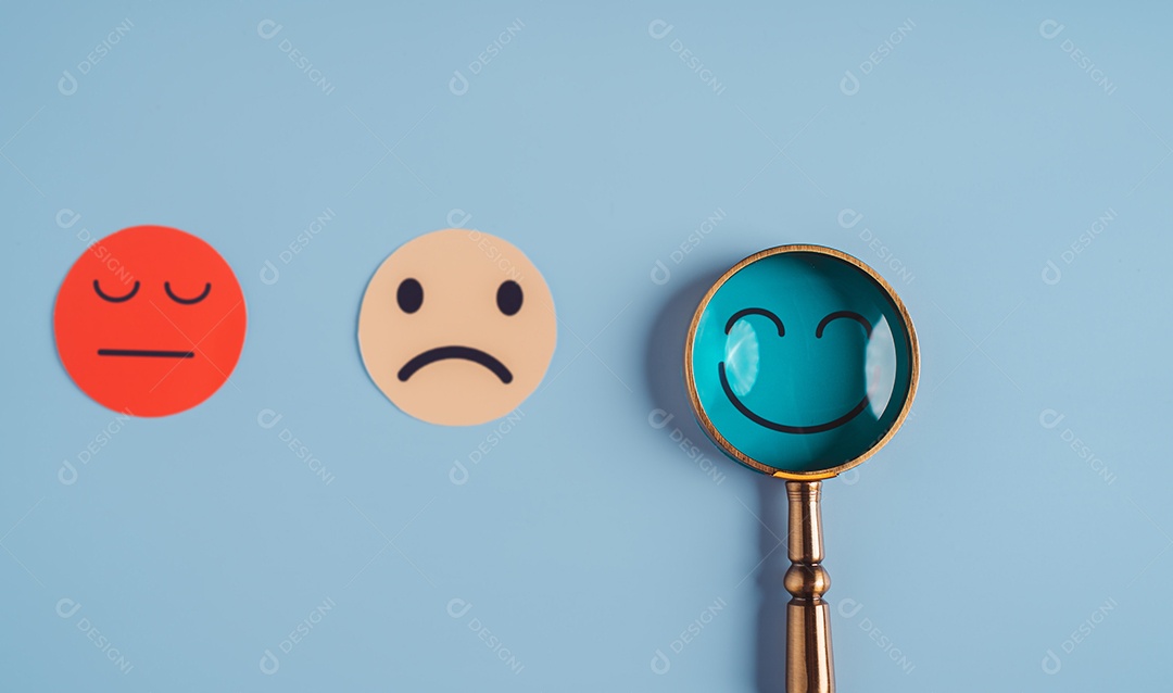 Mão segurando lupa foco selecionado corte de papel de rosto sorridente feliz que está entre várias emoções